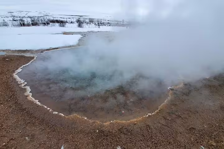 Geothermal hot spring pool steaming in snowy Iceland landscape on private Golden Circle glacier tour
