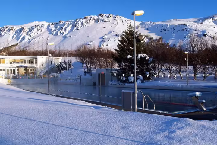 Geothermal outdoor pool in snowy Iceland with mountain backdrop, perfect for Midwinter Warmth tour