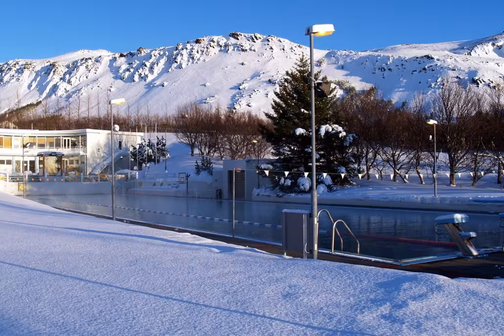Geothermal outdoor pool in snowy Iceland with mountain views, relaxing stop on 02D Midwinter Warmth tour