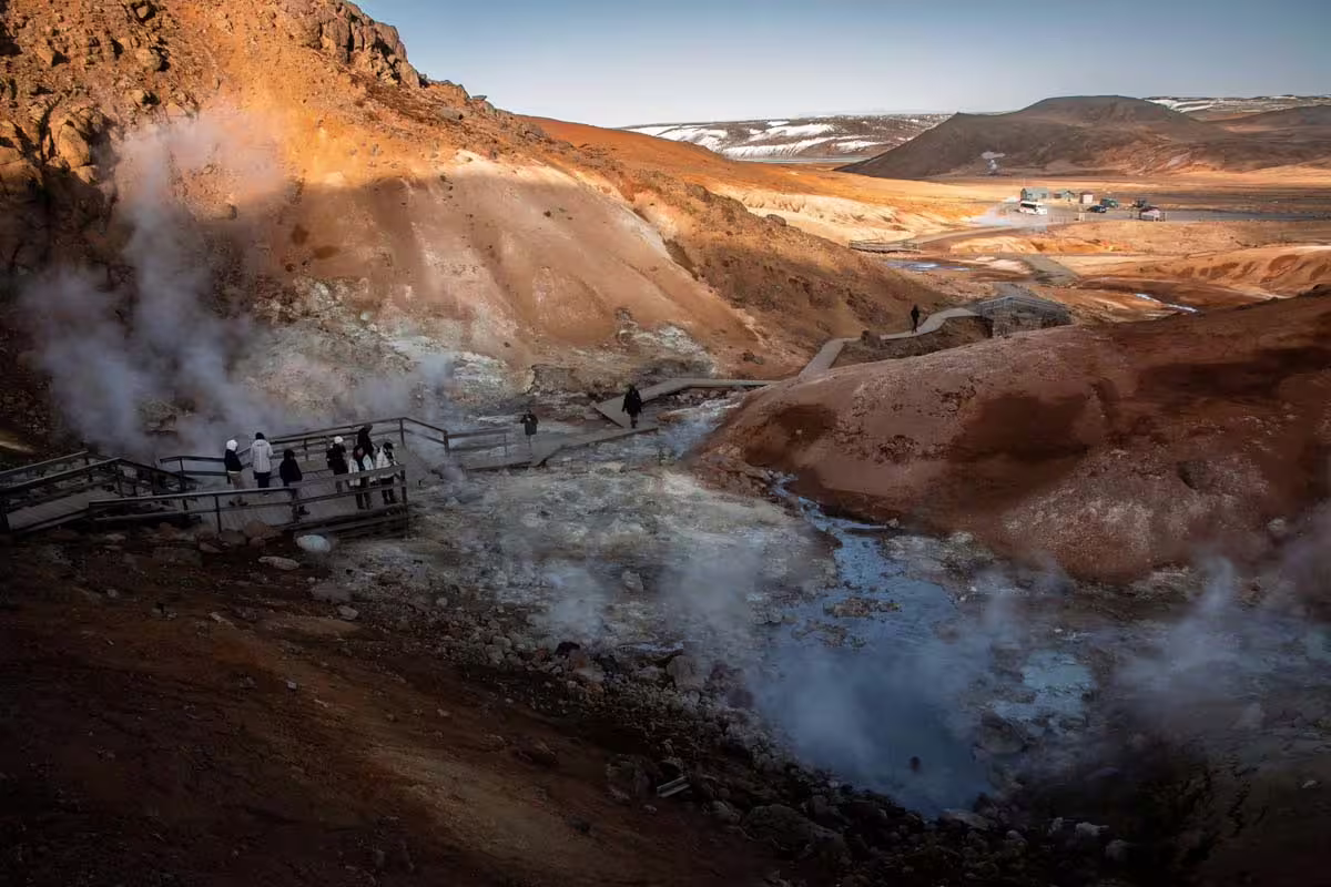 Steaming geothermal vents and colorful volcanic terrain with tourists on walkway near Reykjavik, Iceland