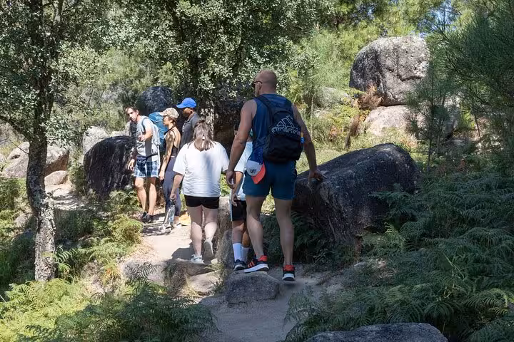 Group of hikers exploring a lush trail in Geres National Park, surrounded by rocks and greenery.