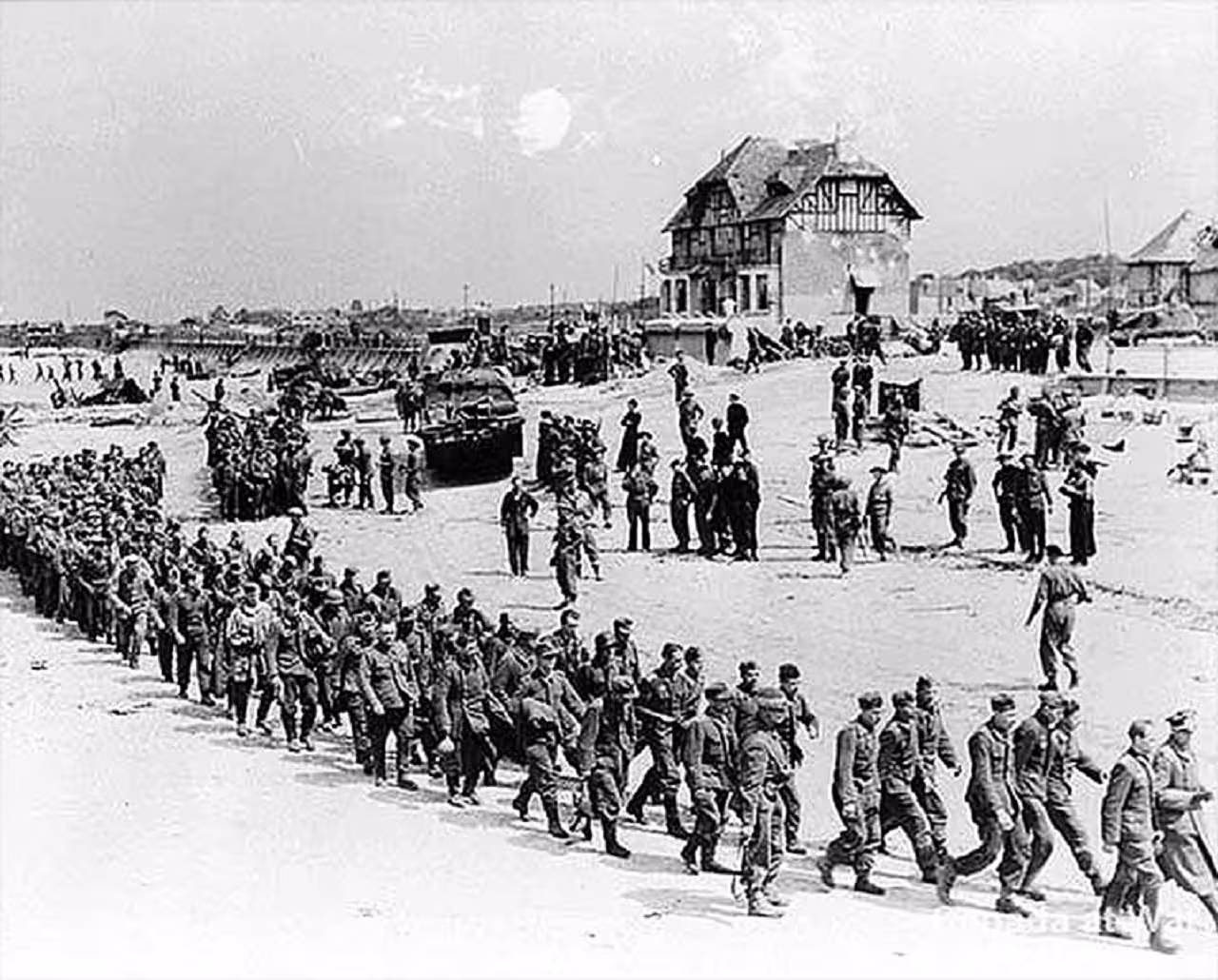 German prisoners of war marching on Normandy beach on D-Day, June 1944, with Allied tanks and troops.