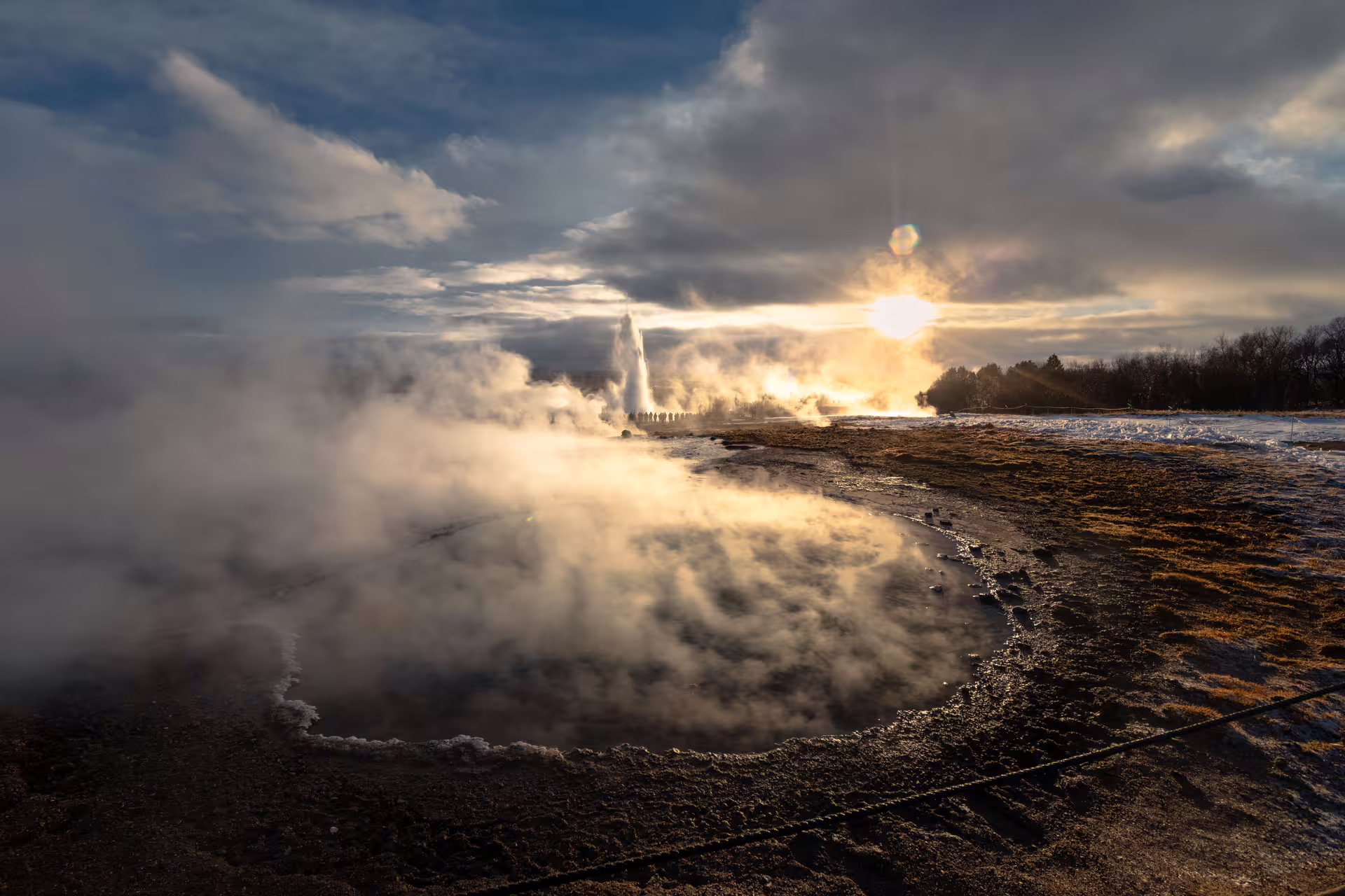 Geysir erupting with steam clouds at golden sunset during Iceland Golden Circle tour