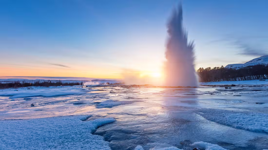 The Geysir geothermal park at sunset with the geysir erupting
