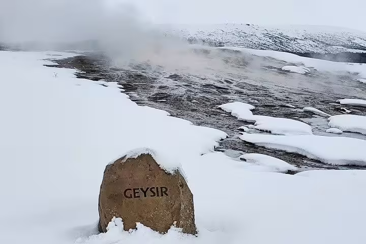 Snow-covered Geysir geothermal area with steaming hot springs and a landmark rock on Iceland's private Golden Circle tour
