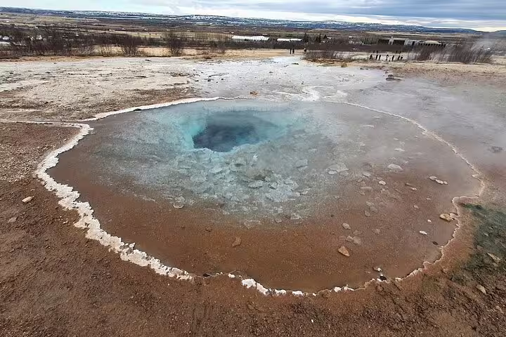 Geysir hot spring pool with vivid blue water surrounded by mineral deposits in Iceland's Golden Circle
