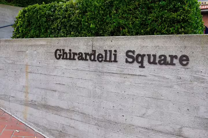 Ghirardelli Square stone sign with green hedges in San Francisco