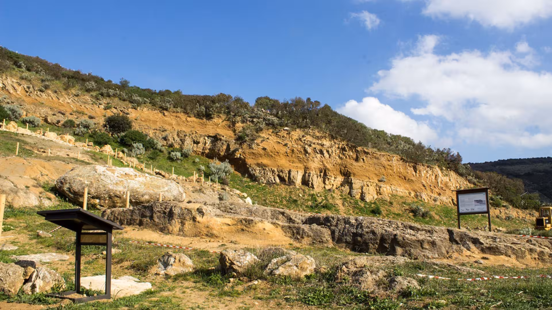 Scenic view of the rugged landscape in Giara Park with rocky terrain and informational signs under a clear sky.