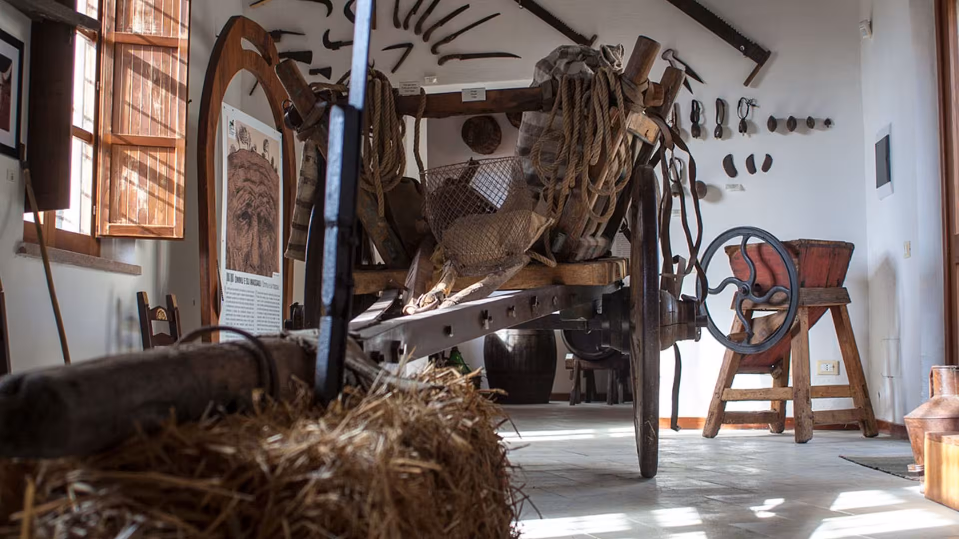 Rustic interior of a traditional museum in Giara Park, showcasing vintage tools and an old wooden cart.