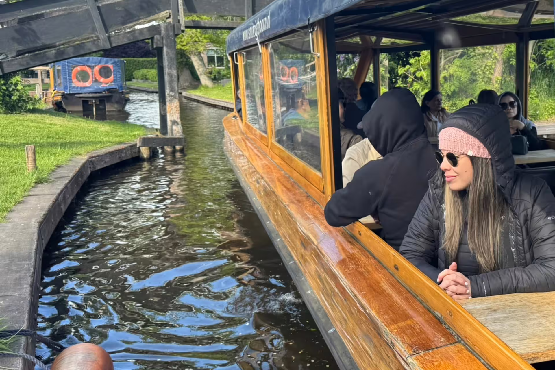 Giethoorn canal cruise boat passing under a wooden bridge, included in Amsterdam Zaanse Schans Volendam tour