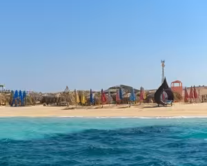 Giftun Island beach with colorful umbrellas, turquoise water, and sandy shore under clear blue sky