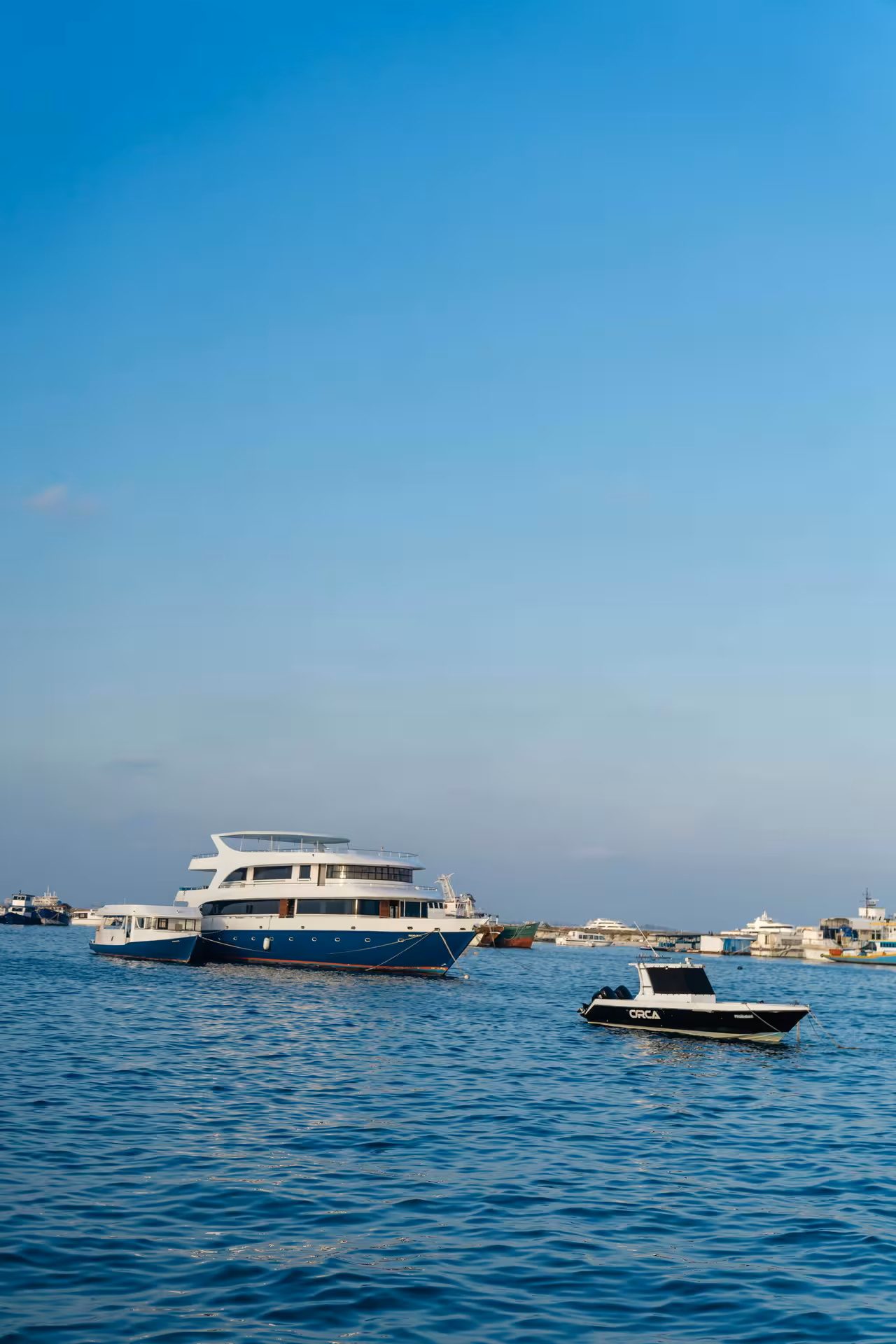 Blue and white luxury yacht anchored near Giftun Island with a small ORCA speedboat in calm turquoise waters