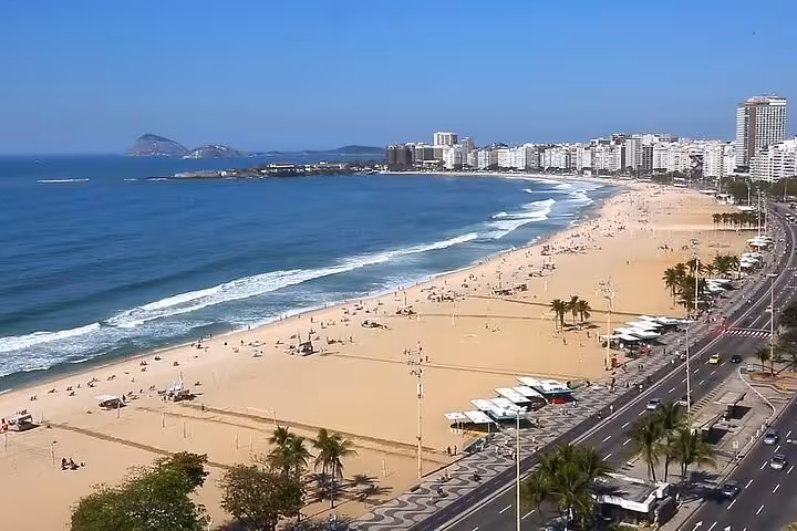 Aerial view of Barra da Tijuca beach with high-rise buildings and a busy coastal road in Rio de Janeiro, Brazil.