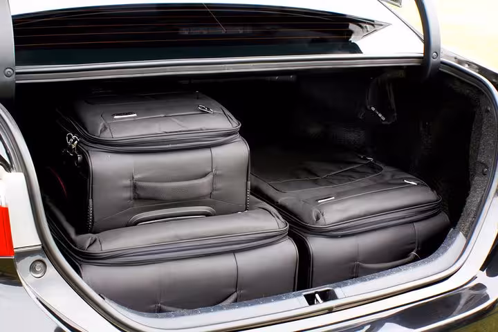 Spacious car trunk neatly packed with multiple black suitcases, ideal for airport shuttle service to Rio hotels.