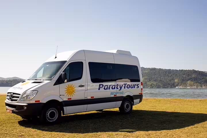 Comfortable Paraty Tours shuttle van parked by the scenic shoreline, offering exclusive airport transfers to Rio.