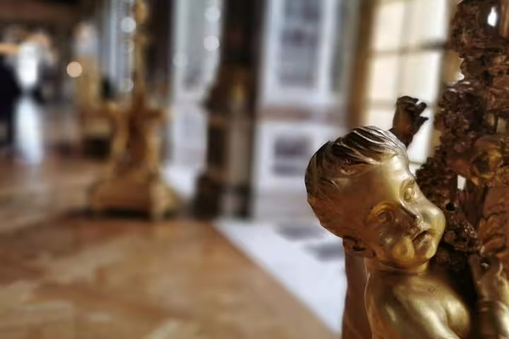 Close-up of gilded cherub sculpture inside Versailles Palace, part of guided skip-the-line tour experience