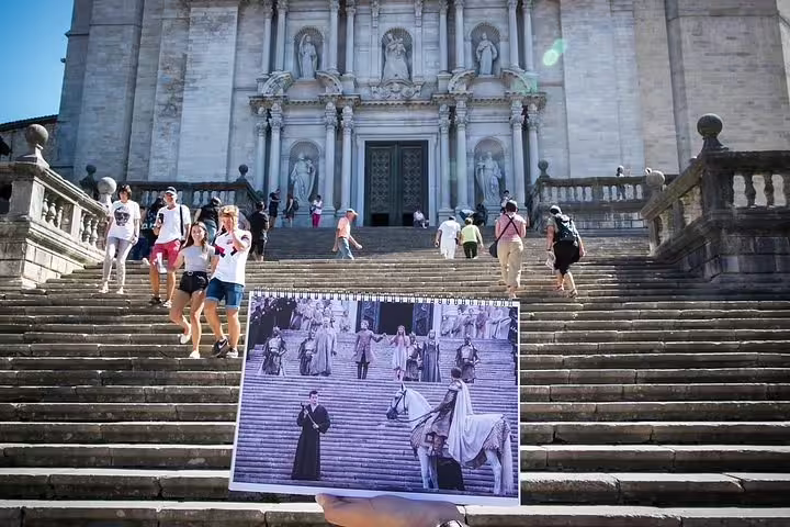 Tourists exploring the historic steps of Girona Cathedral with a movie scene overlay.