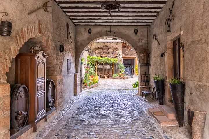 Charming cobblestone courtyard in Girona with rustic arches and vibrant greenery on a local city walk.