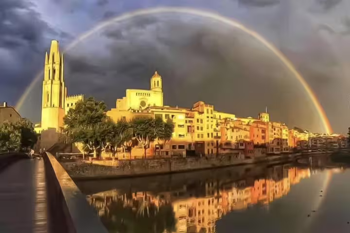 A stunning rainbow arches over Girona's historic skyline and the Onyar River, capturing the charm of a Costa Brava tour.