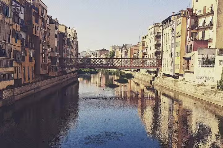 Picturesque Girona with colorful riverside buildings and iconic bridge, offering a glimpse into the city's historic charm.