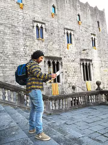 Traveler exploring a historic stone building in a medieval Catalonian village, perfect for a cultural day trip and scenic lake lunch.