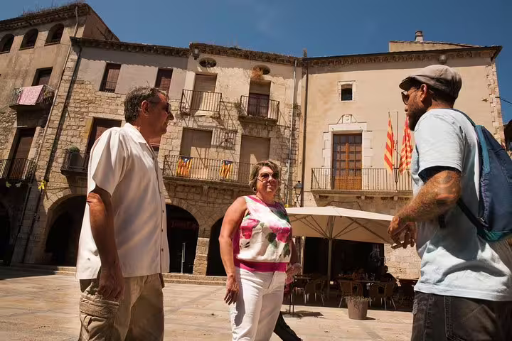 Travelers enjoy a guided exploration of a medieval village in Catalonia, showcasing historic architecture and vibrant local culture.