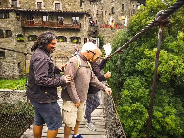 Tourists enjoy a scenic view from a suspension bridge in a medieval Catalonia village, part of a full-day guided tour.