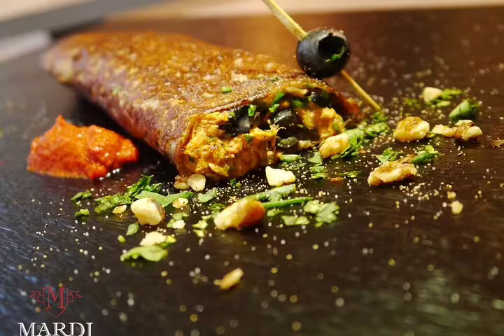 Savory crepe filled with black olives and herbs on a slate plate with tomato sauce