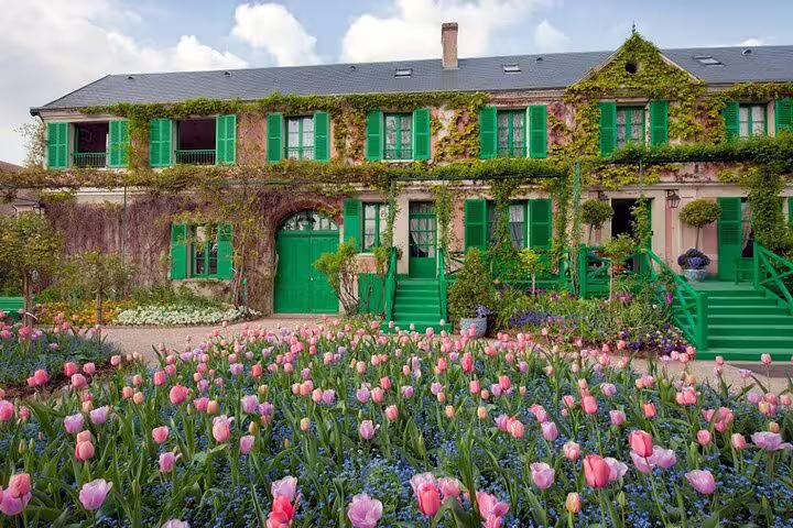 Claude Monet's house in Giverny with green shutters and pink tulip garden in bloom