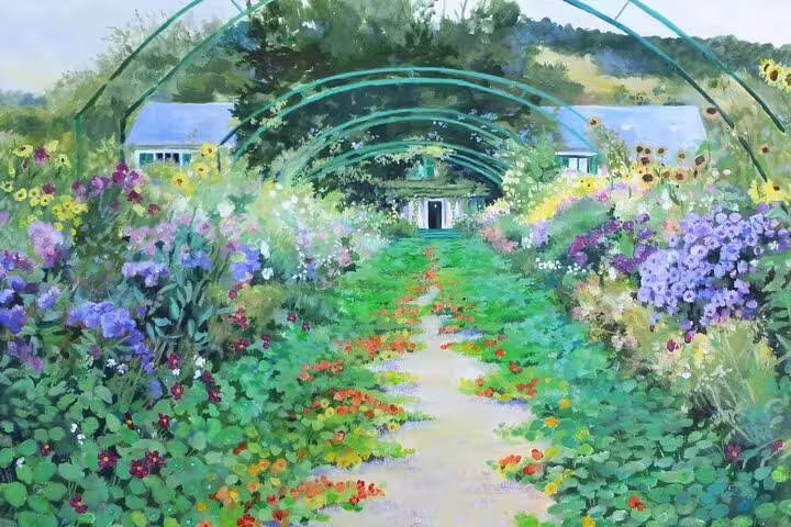 Monet's garden in Giverny with arched trellis pathway lined with colorful blooming flowers leading to a house