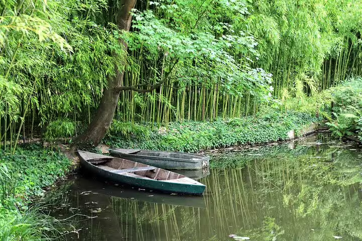 Two wooden rowboats moored on a tranquil pond surrounded by bamboo and lush greenery at Giverny