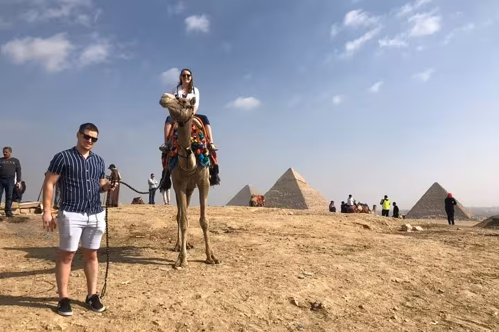 Camel ride experience at Giza Plateau with pyramids in the background on an all-inclusive Giza tour and Sphinx visit