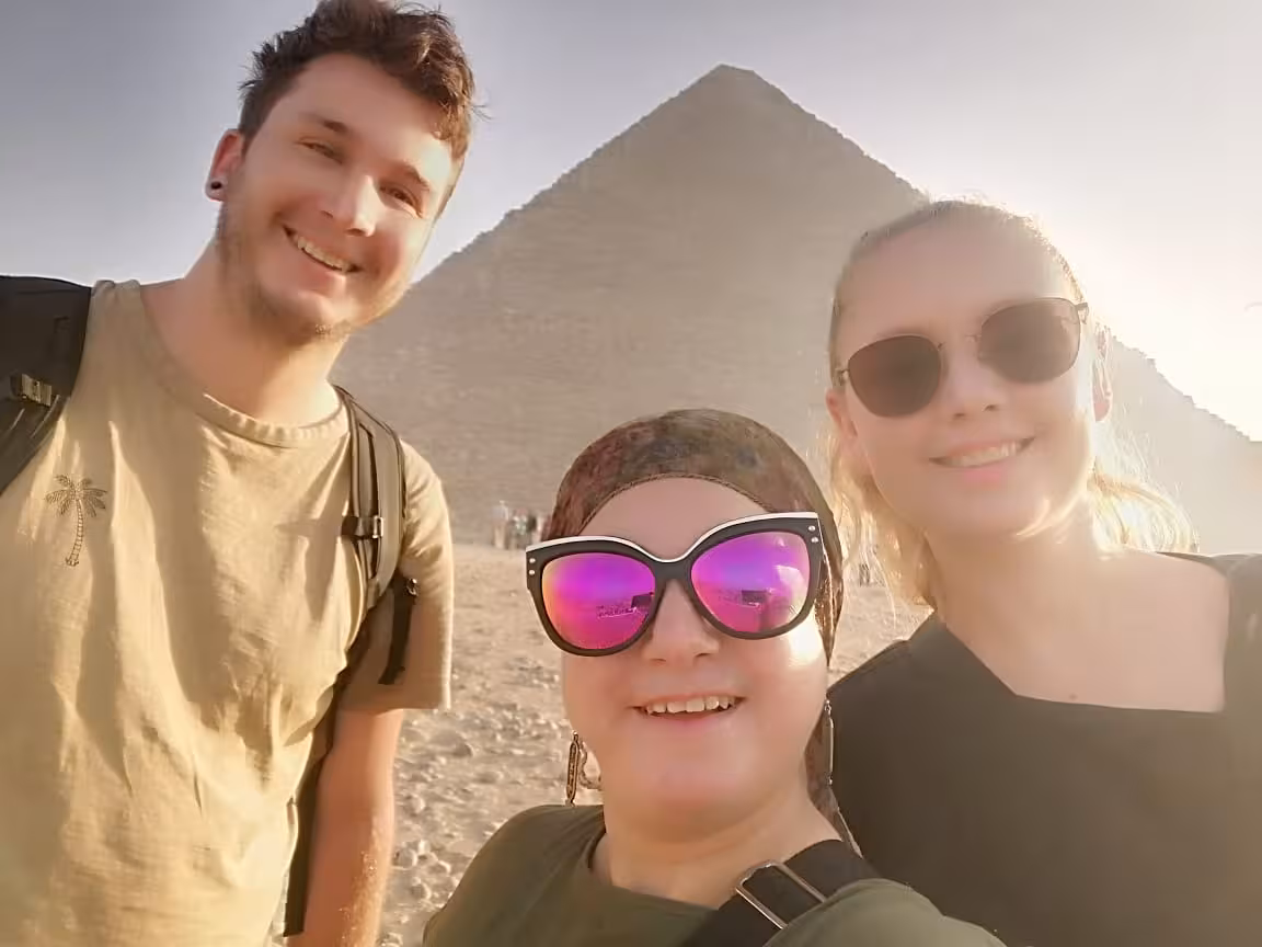 Group selfie with Giza Pyramid backdrop in Cairo, part of a camel ride experience and lunch tour package