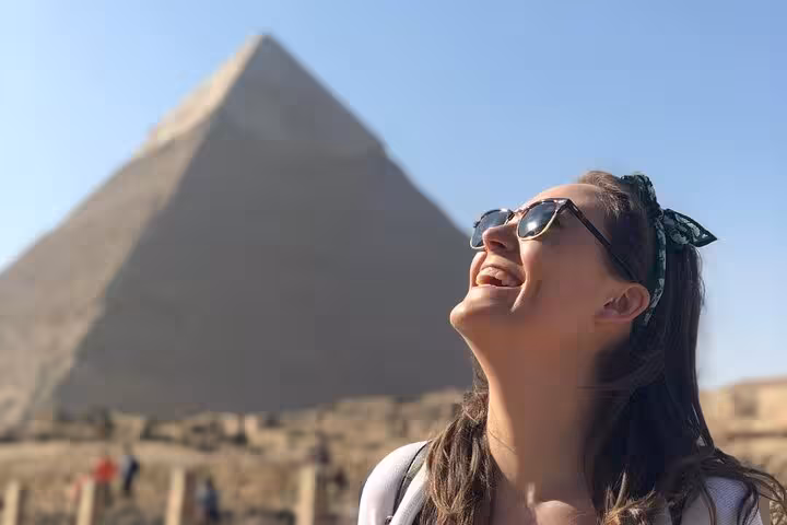 Happy traveler at the Great Pyramid of Giza during an all inclusive tour with pyramid entry, Sphinx visit and camel ride