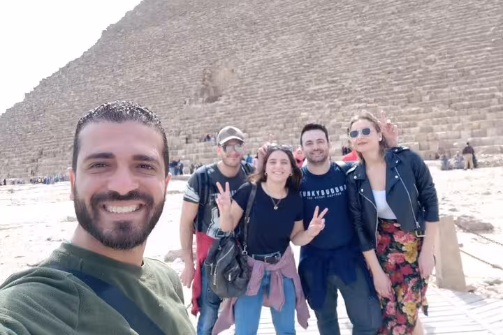 Happy travelers pose with a guide at the Great Pyramid of Giza on an all-inclusive pyramid entry tour