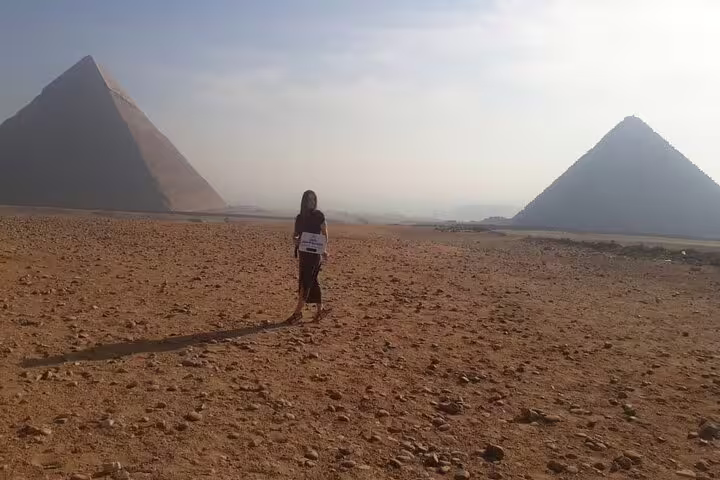 Visitor walking in Giza desert between pyramids on Port Said shore excursion with lunch by the Nile River