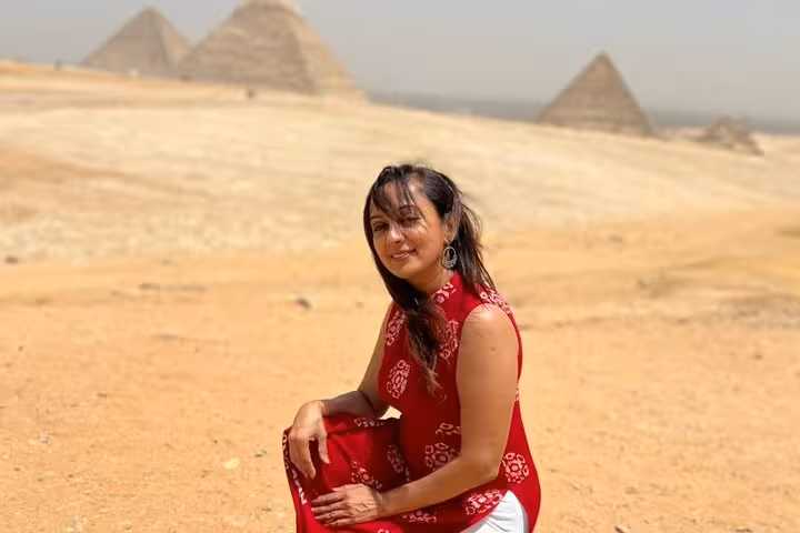 Woman in desert with Giza Pyramids behind on private Cairo tour featuring ATV ride, camel trek and dinner cruise