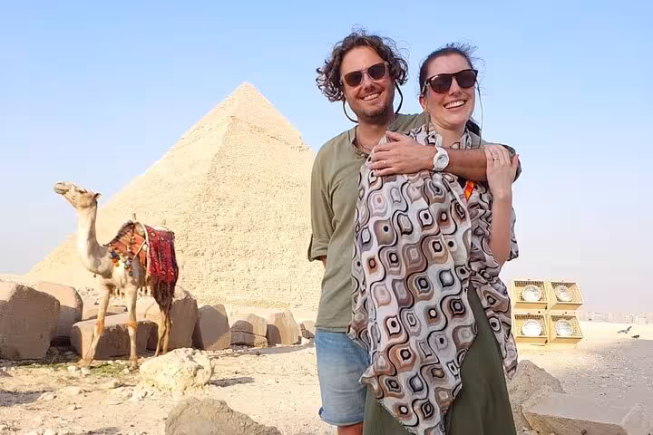 Private all-inclusive Giza Pyramids tour from Cairo Airport with travelers and camel near Great Pyramid