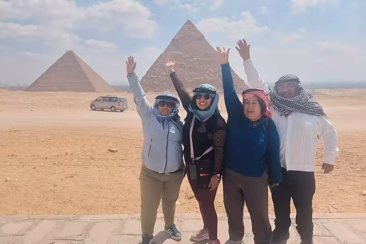 Travelers posing with raised hands at Giza Pyramids, Cairo and Giza private sightseeing tour photo stop