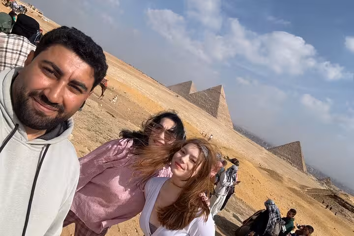 Tour photo at the Giza Pyramids with travelers and guide on Cairo desert plateau, Egypt day tour