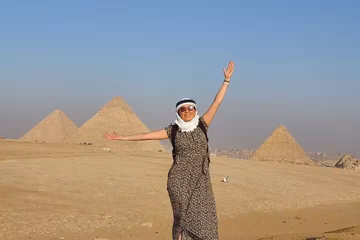 Traveler posing with arms raised at the Giza Pyramids on an all-inclusive guided Cairo day tour