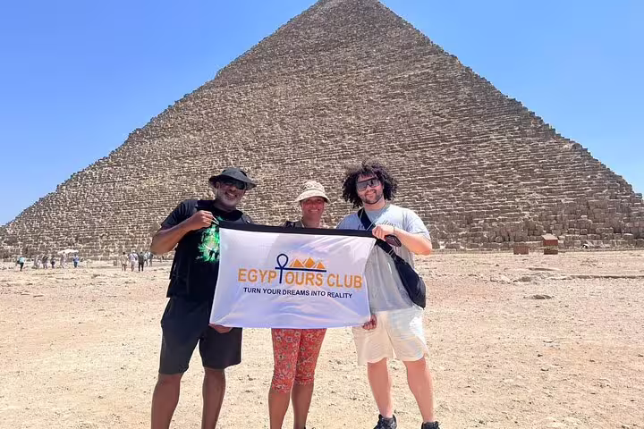 Travelers holding banner in front of the Great Pyramid of Khufu on a Giza Pyramids private tour from Cairo