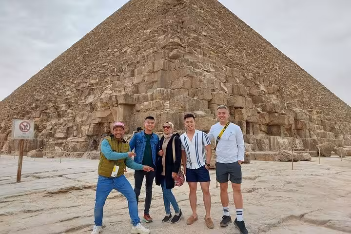 Visitors posing by the Great Pyramid of Khufu on a private Giza pyramids tour, Cairo full-day excursion