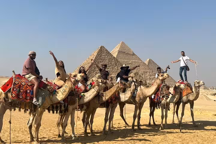 Group camel ride at Giza Pyramids, Egypt, on private tour with desert views and iconic pyramids backdrop