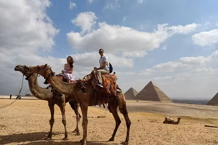 Tourists on camel ride at Giza Pyramids desert viewpoint, part of private Giza tour with quad bike option