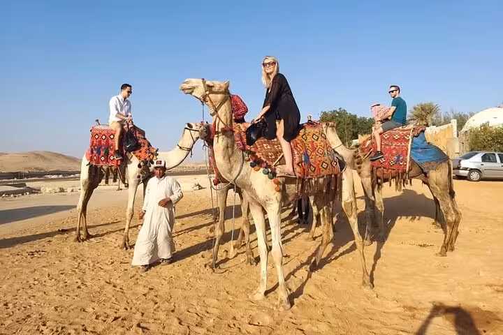 Tourists on camel ride in the Giza desert near the pyramids, private tour with guide and scenic views