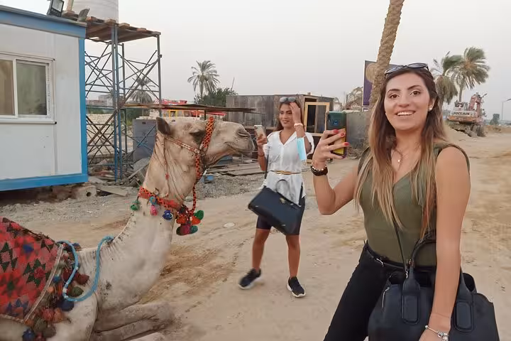 Travelers taking selfies with a decorated camel on a private Giza tour with camel ride and quad bike option