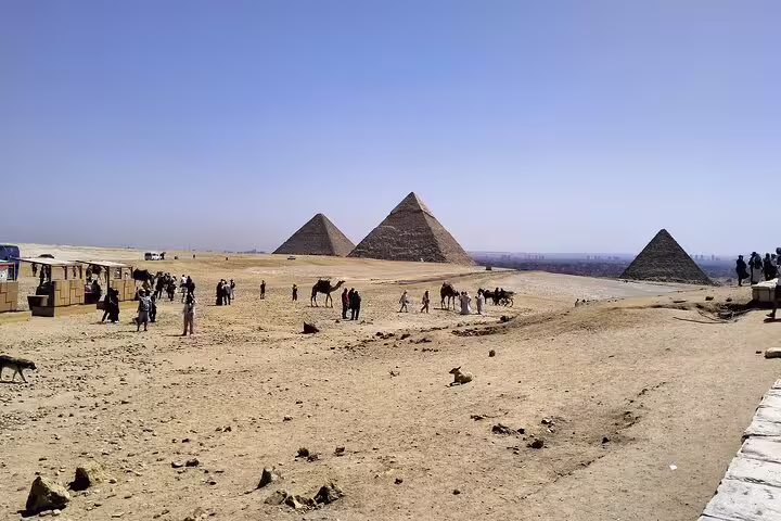 Panoramic Giza Plateau with pyramids, camels and visitors during a 14-day Egypt Nile and Sahara desert bus tour