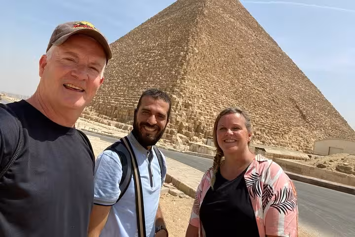 Guests with local guide posing by the Great Pyramid of Giza on a private tour with ATV, camel ride and Nile cruise