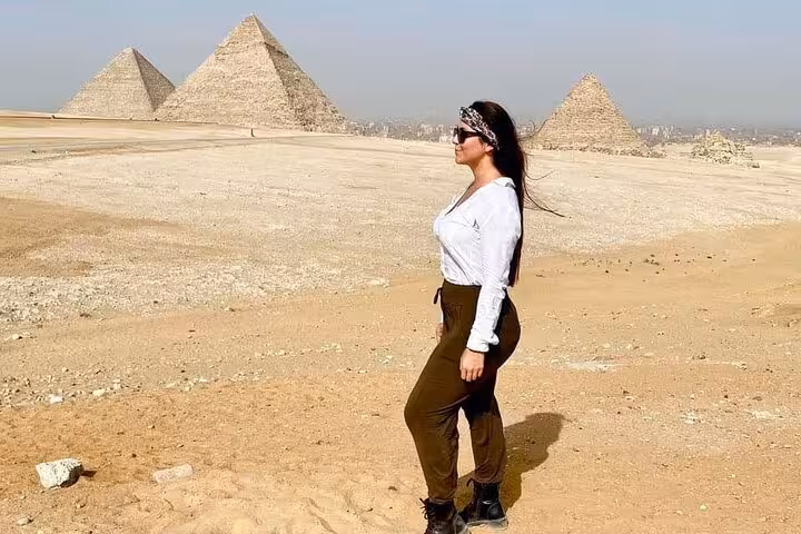 Traveler posing in Giza desert with Great Pyramids backdrop on private tour with ATV ride, camel trek and lunch